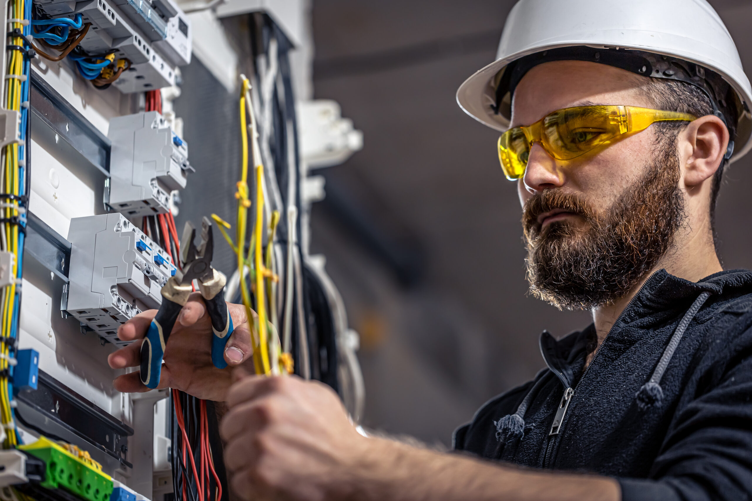 male electrician works switchboard with electrical connecting cable scaled